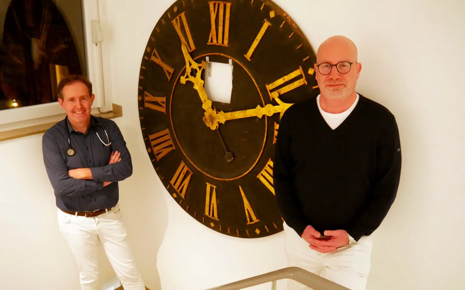 Vater Heede war ein großer Uhrenliebhaber. Hier stehen Matthias und Christian Heede vor einem ehemaligen Zifferblatt einer Kirchturmuhr in der Praxis. Foto: cj