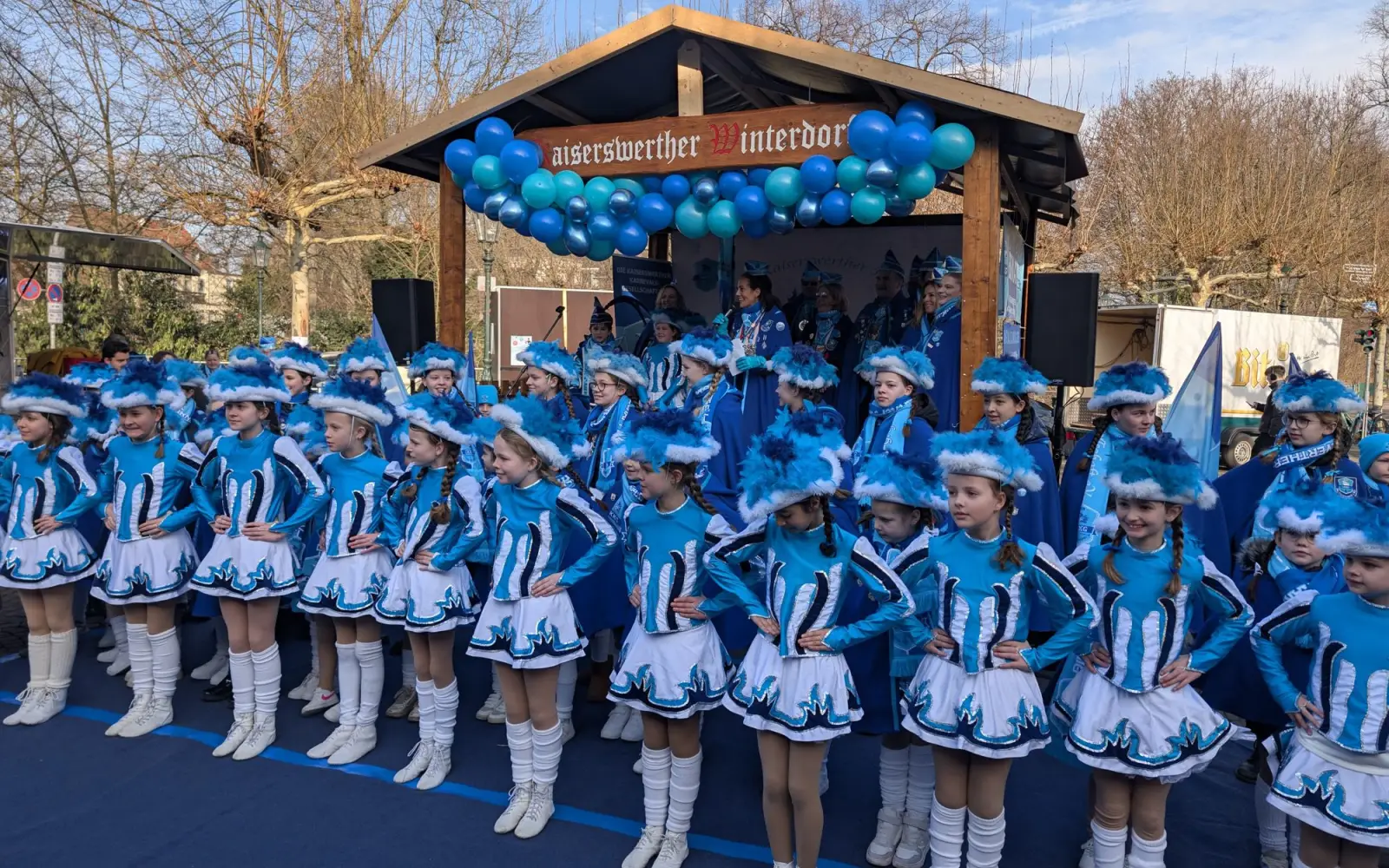DKKG-Präsidentin Nicole Berger (auf der Bühne mit Mikrofon) begrüßte die Gäste zum Biwak, während sich die Kindertanzgarde in ihren blau-weißen Uniformen vor der Bühne präsentierte. Foto: ah