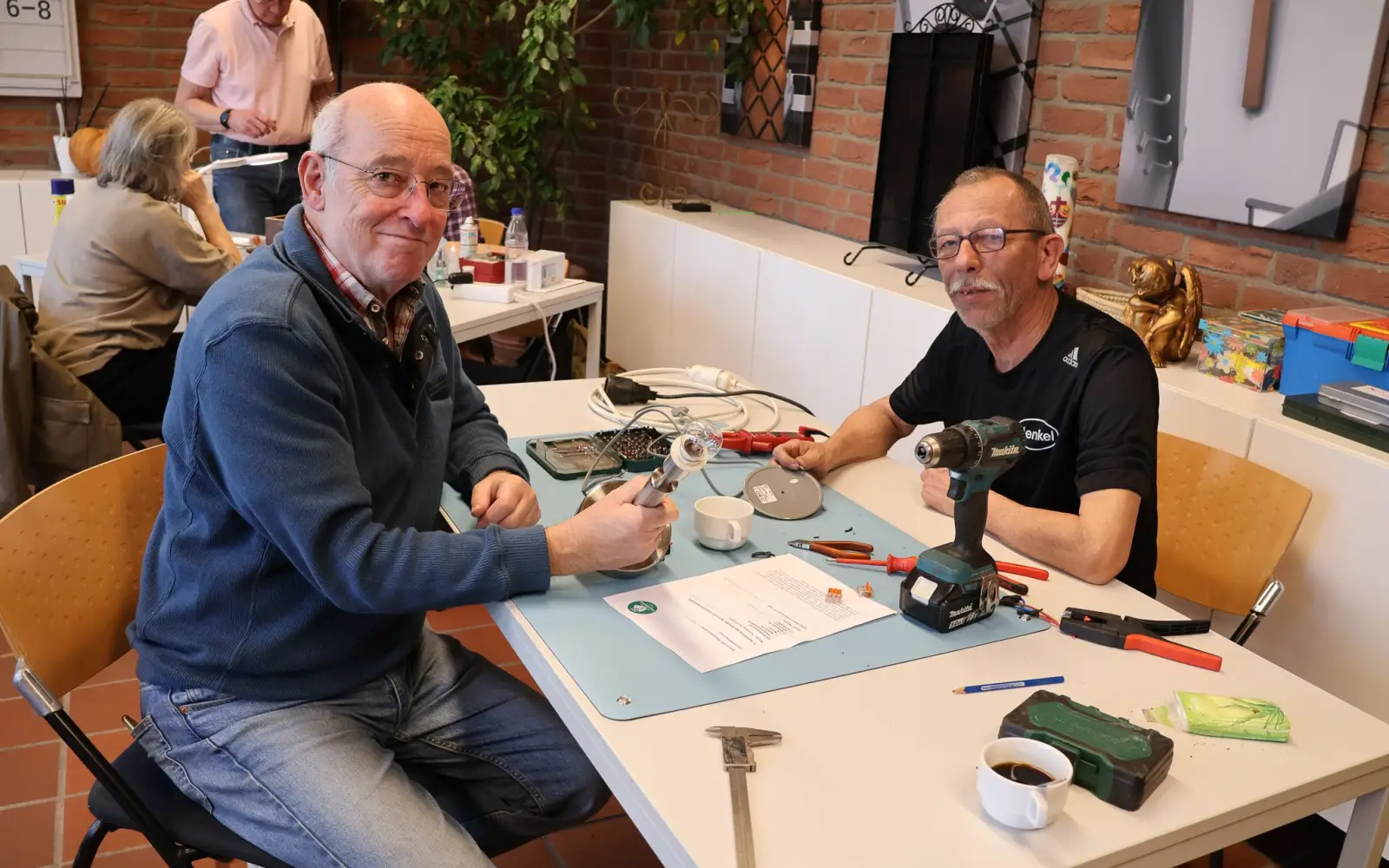 Ein Besucher freut sich über die von Elektromeister Michael Kiefer (rechts) reparierte Lampe im Reparaturcafé Kaiserswerth. Foto: ah