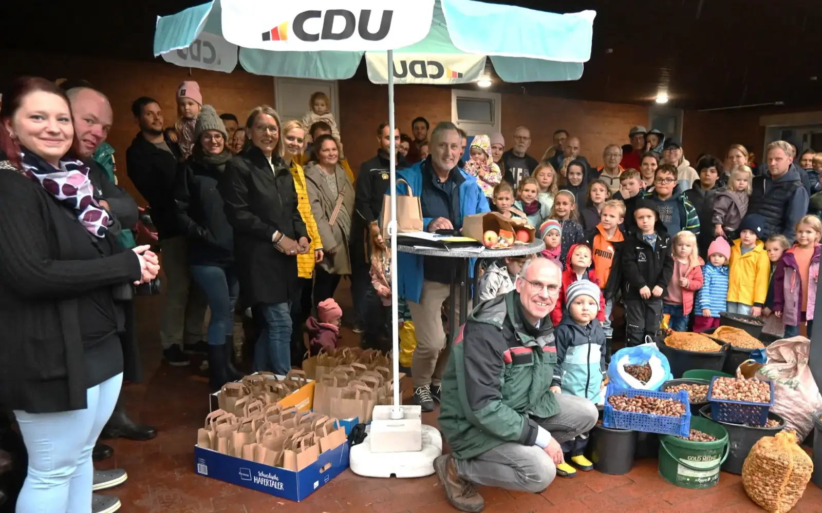 Viele Mädchen und Jungen kamen mit ihren Eltern oder Großeltern, um die Eicheln an Stadtförster Stefan Jeschke (vorne) abzugeben. Wolfgang Schwertner und Beate Kampf (unter dem Schirm) verteilten für den CDU-Vorstand MES zur Belohnung Süßes und Gesun