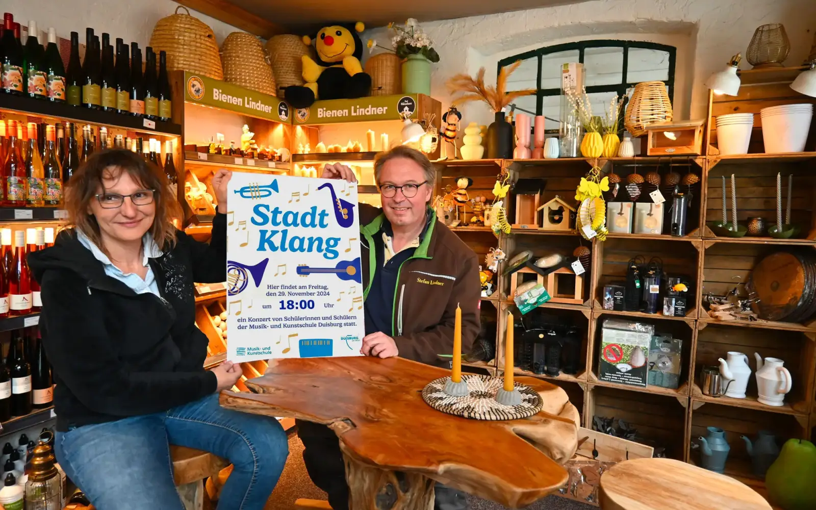 Sabine und Stefan Lindner präsentieren das Plakat zum „Stadtklang“-Konzert, das am Freitag, 29. November 2024, bei „Bienen Lindner“ in Serm stattfindet. Foto: sam