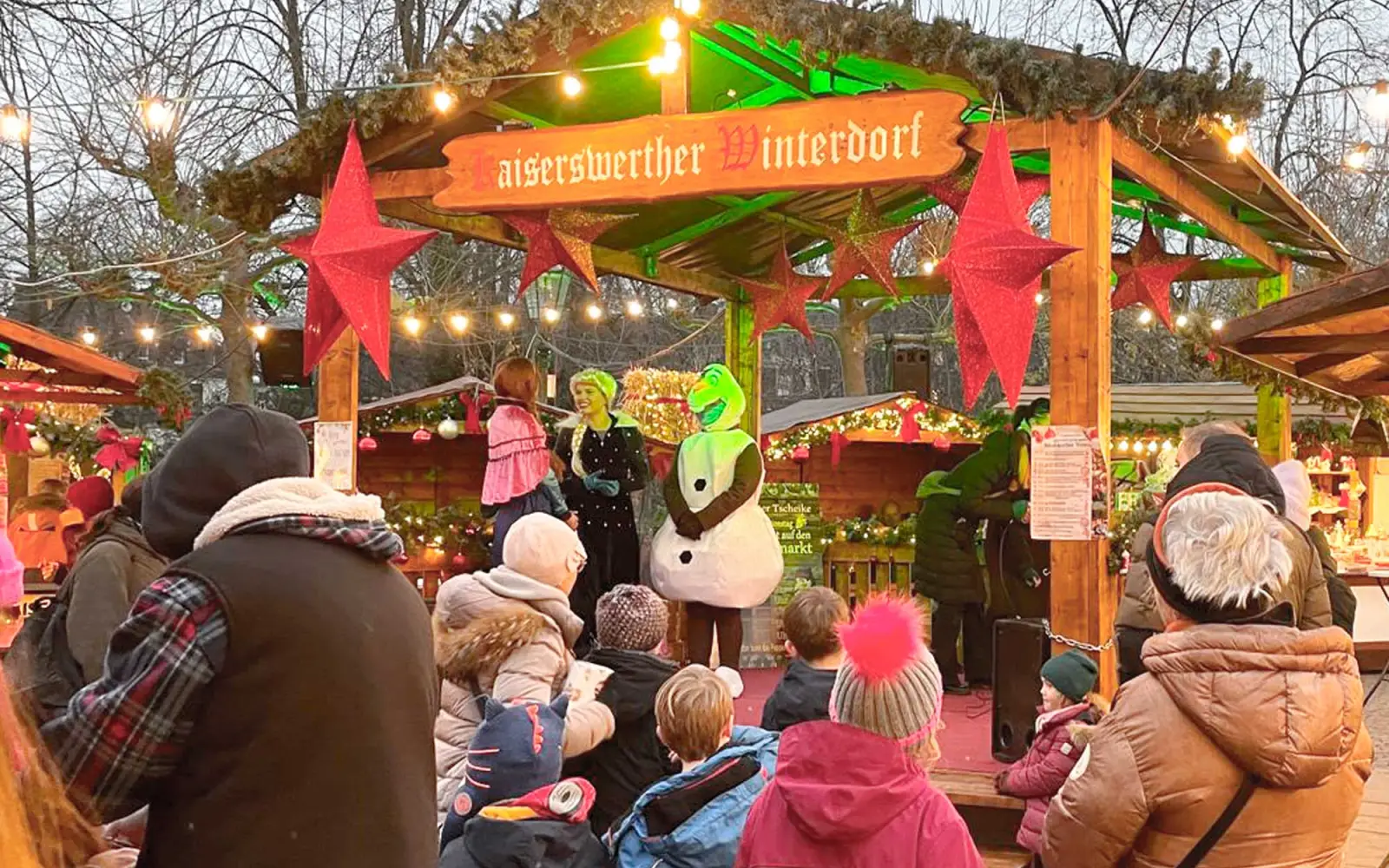 Zahlreiche Kinder verfolgen gespannt die Ziehung der Gewinner, begleitet von Mickey, Mini und Olaf auf der festlich geschmückten Bühne. Foto: kw