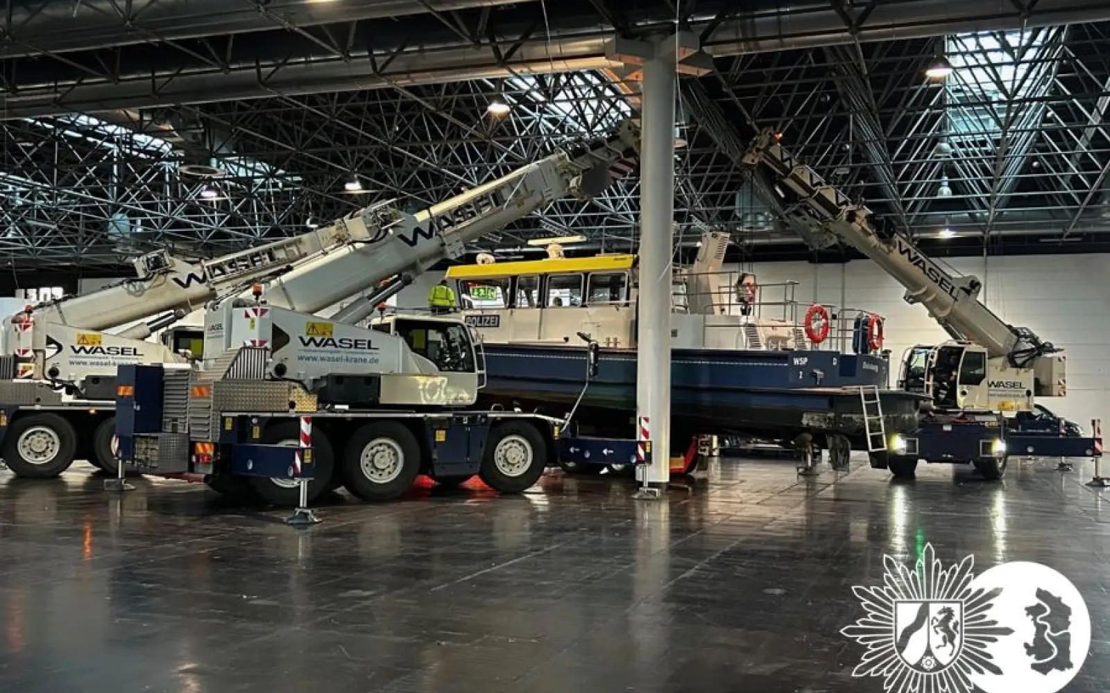 Mehrere Kräne hieven das Polizeiboot WSP 2 in der Messehalle 14 der Düsseldorfer Messe auf das Ausstellungsgestell. Foto: Polizei NRW