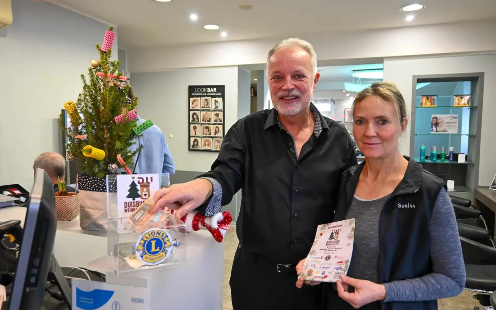 Spendendosen, in denen Geld für die Aktion „Duisburger Weihnachtslicht“ gesammelt wird, stehen in zahlreichen Geschäften, so auch im Duisburger Süden. Mit gutem Beispiel ging Markus Lotze in seinem Salon in Großenbaum voran, der gerne das soziale Engagement seiner Mitarbeiterin Sorina Kuhnt unterstützt und das Prinzip „Duisburger helfen Duisburger“ toll findet. Foto: sam