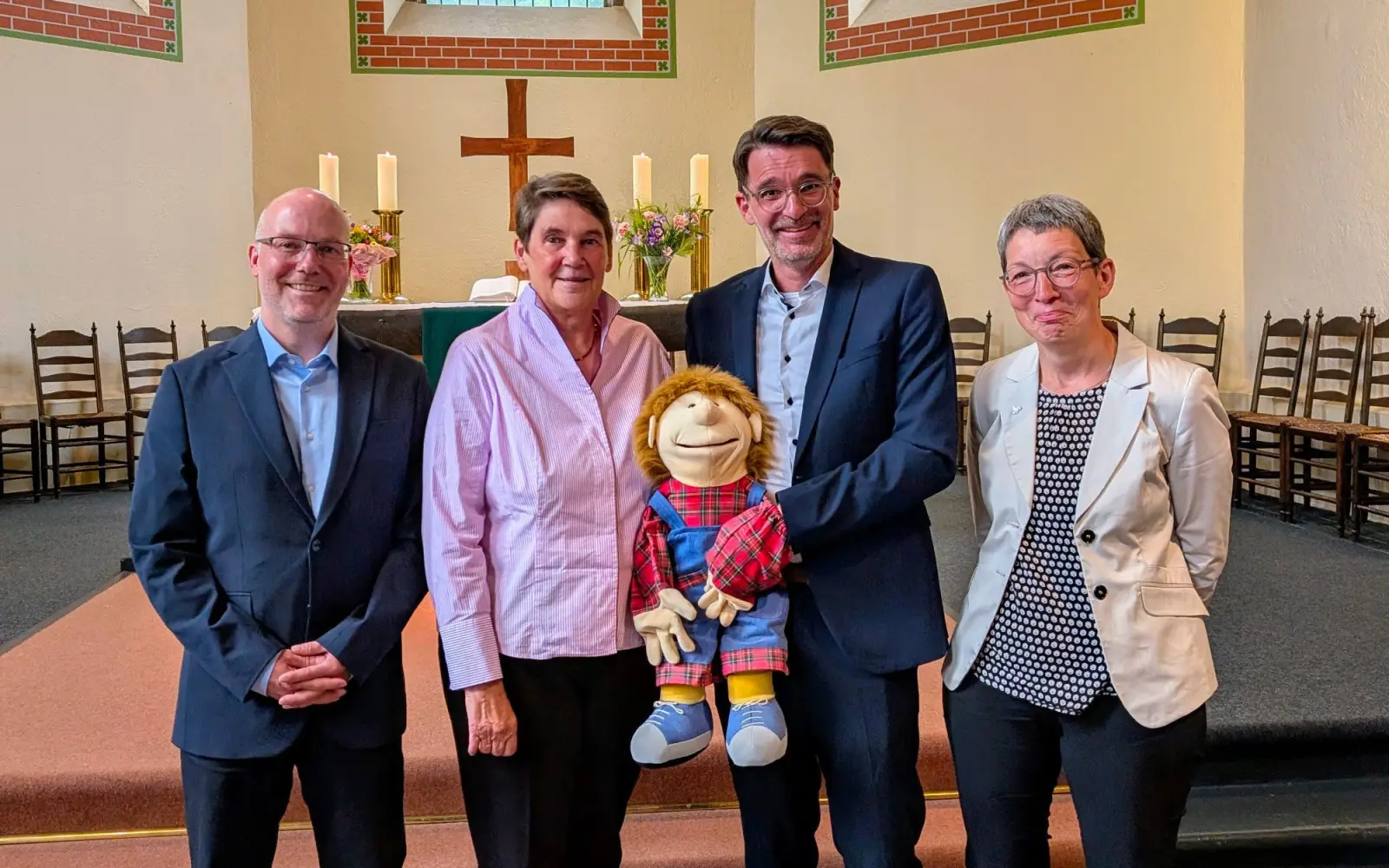 Der stellvertretende Schulleiter Marc Wirths, die scheidende Schulleiterin Astrid Hofmeister, ihr Nachfolger Gunnar Gurski und Bereichsleiterin Monika Schult (von links) bei der Übergabe der Handpuppe „Willy“. Foto: Kaiserswerther Diakonie/A. Debusmann