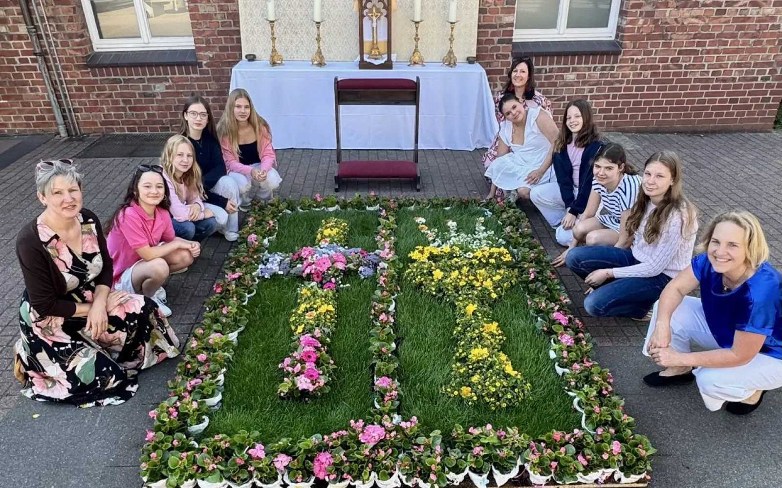 Schülerinnen der 7. Klasse gestalten mit Geduld und Kreativität einen Blumenteppich vor dem Altar auf dem Schulhof des Suitbertus-Gymnasiums. Foto: os