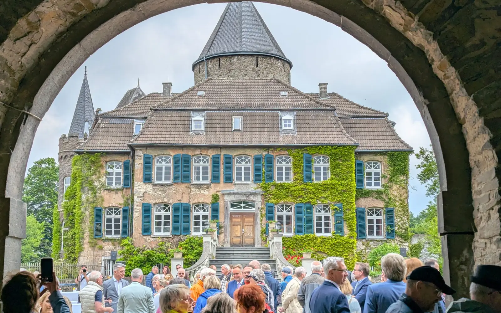 Blick auf Schloss Linnep durch den Torbogen mit zahlreichen bereits eingetroffenen Besucherinnen und Besuchern. Foto: ah