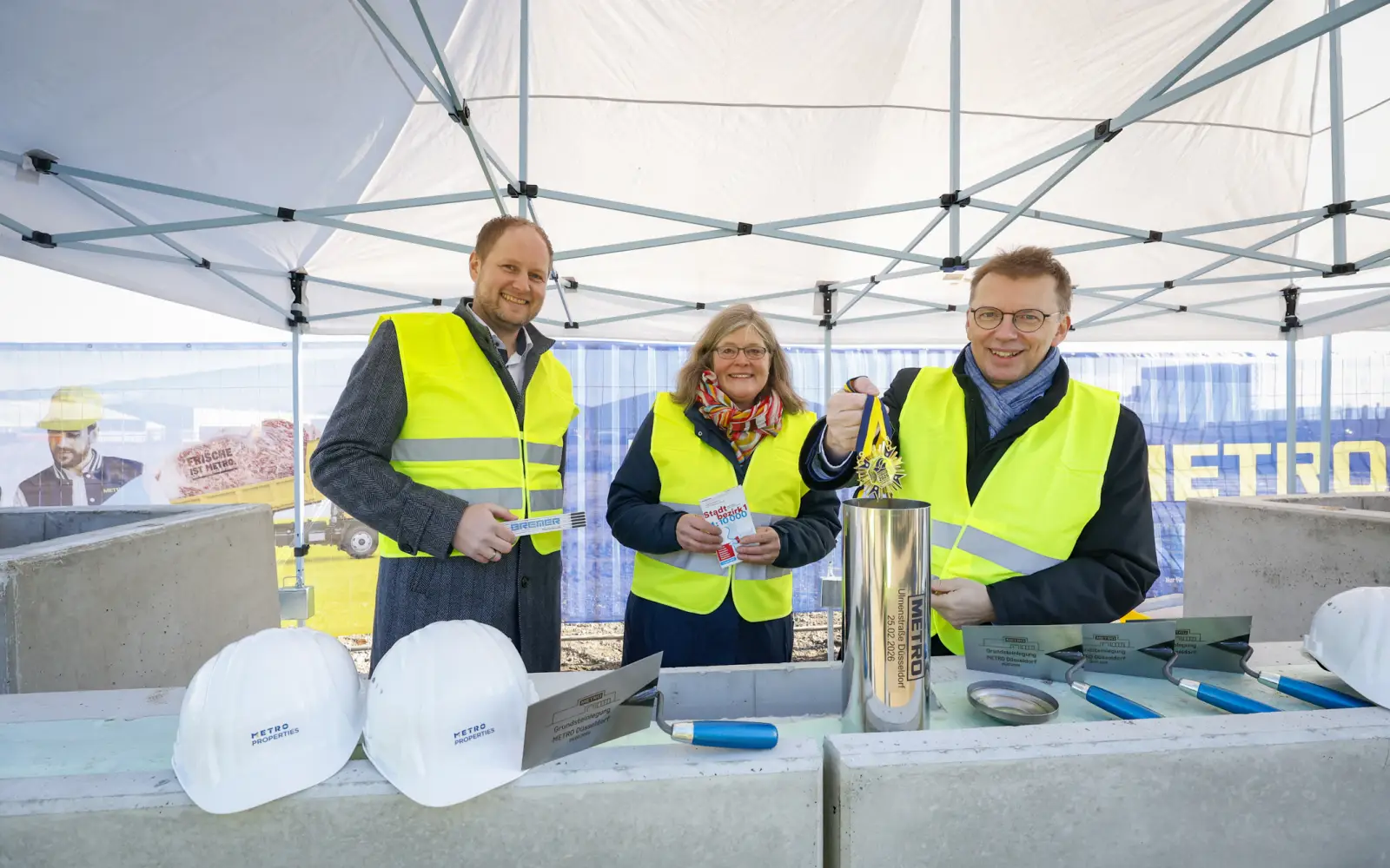 Florian Röhrs (BREMER West), Bezirksbürgermeisterin Annette Klinke und Roland Ruffing (METRO Deutschland) befüllen die Zeitkapsel, die im Rahmen der Grundsteinlegung in das Fundament eingelassen wurde. Foto: METRO Deutschland