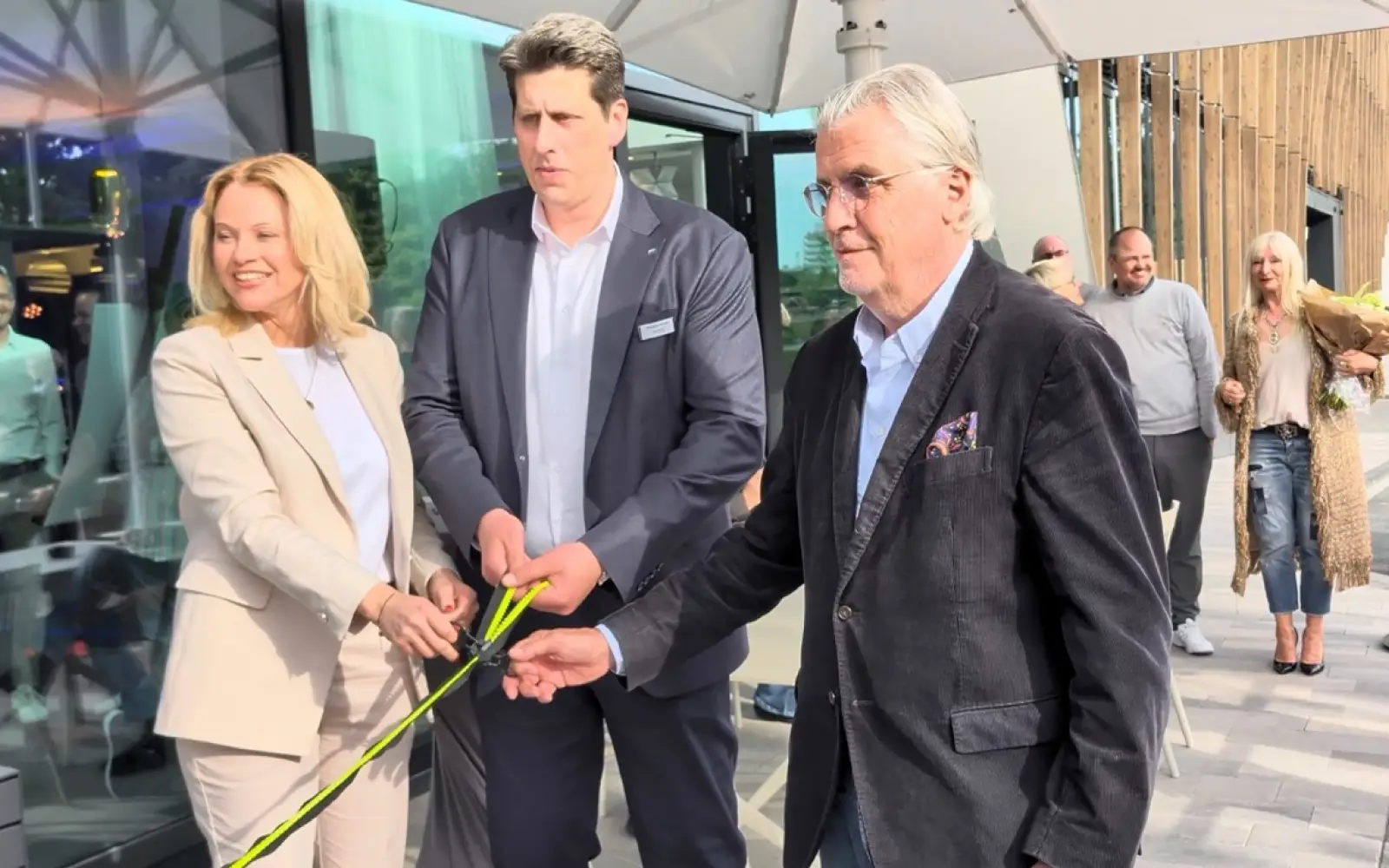 Stefanie Brandes, Christian Schulte und Patrick Schwarz-Schütte (von links) öffnen statt eines Bandes einen Reißverschluss und verweisen damit auf die Modegeschichte des Standorts. Foto: ah