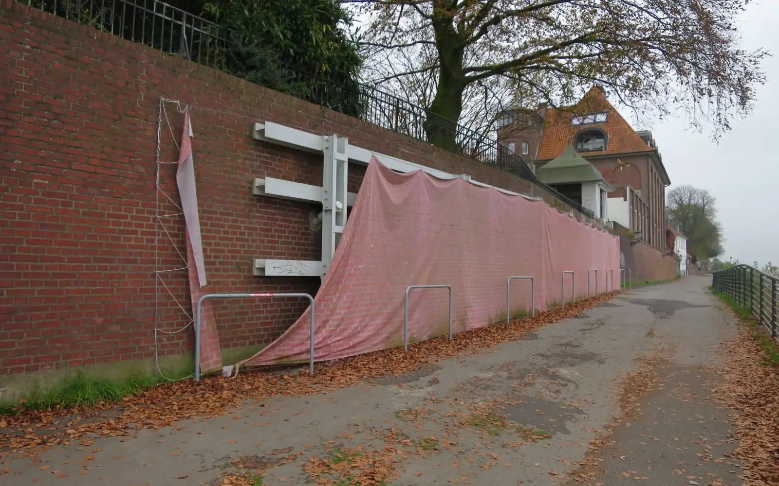 Die verwitterte und beschädigte Abdeckplane des Stützgerüsts an der Kaiserswerther Hochwasserschutzmauer. Foto: hs