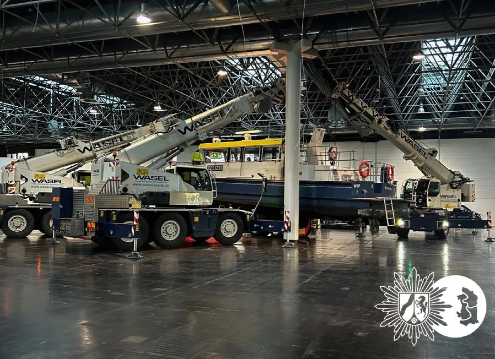 Mehrere Kräne hieven das Polizeiboot WSP 2 in der Messehalle 14 der Düsseldorfer Messe auf das Ausstellungsgestell. Foto: Polizei NRW
