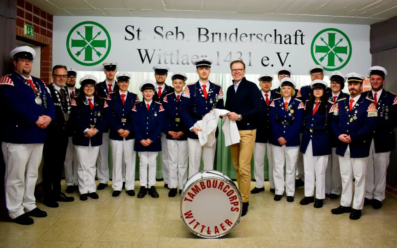 Dominik Schlarmann bei der symbolischen Übergabe der Spende an den stellvertretenden Major des Tambourcorps, Niclas Busch. Vorne links ist der Vorsitzende des Tambourcorps, Christian Jakobs, zu sehen, neben ihm steht der Brudermeister der St. Sebasti