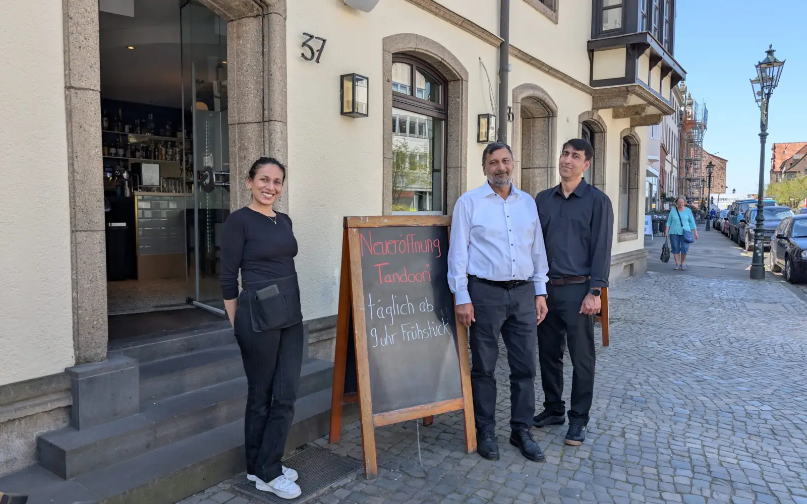 Inhaber Amir Khan (Mitte) mit Mitarbeitenden vor dem neuen Tandoori am Kaiserswerther Markt 37. Foto: ah