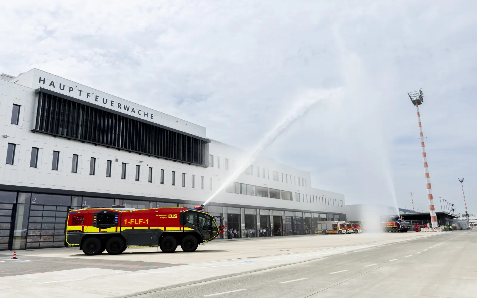 Mit Wasserfontänen aus zwei Panther-Löschfahrzeugen feierte die Flughafenfeuerwehr die Einweihung ihrer neuen Hauptwache. Foto: Flughafen Düsseldorf