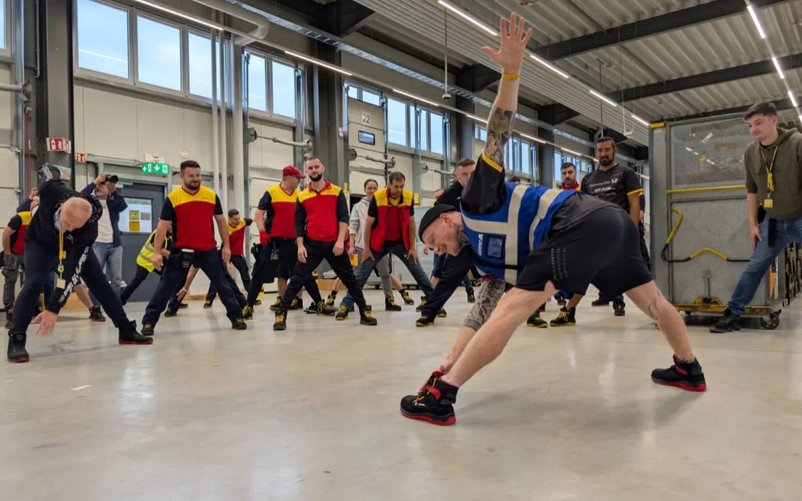 Sportwissenschaftler Hanjo Fritzsche macht den Zustellern im Stützpunkt am Kieshecker Weg 98 die Dehnübungen vor, bevor die Touren beginnen. Foto: ah