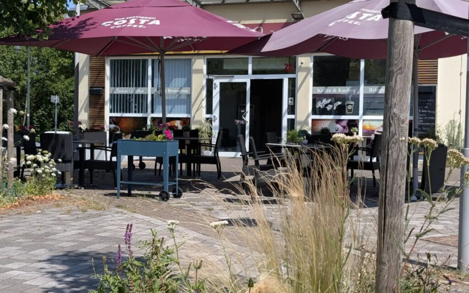 Vor der Bäckerei Wittlaer spenden Sonnenschirme den Schatten, den die vertrockneten Bäume auf dem Platz nicht mehr bieten. Foto: ah