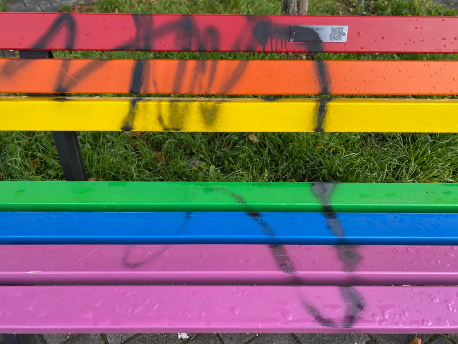 Unbekannte haben die Regenbogenbank am Angermunder Kreisverkehr erneut beschmiert, auch das Hinweisschild ist übersprüht. Foto: os