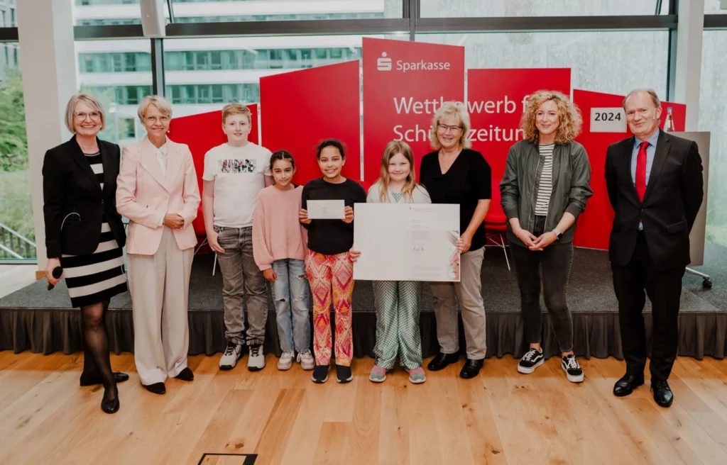 Schulministerin Dorothee Feller (2. von links) und RSGV-Präsident Michael Breuer (rechts) gratulierten einigen Teilnehmenden der Rahmer Schülerzeitungs-AG mit ihrer Leiterin Sabine Merz (3. von rechts). Die „Flinke Feder“ wird von Louisa Zeunert layoutet (2. von rechts). Durch die Feierstunde führte Margareta Rieck. Foto: RSGV